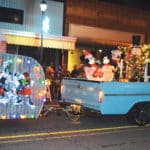 A blue truck decorated with Mickey and Minnie Mouse and Christmas lights moves through the Attalla Christmas parade.