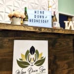 The main counter in Wine Down Spa is decorated with flowers, a logo and a small sign that reads 'Wine Down Wednesday.'