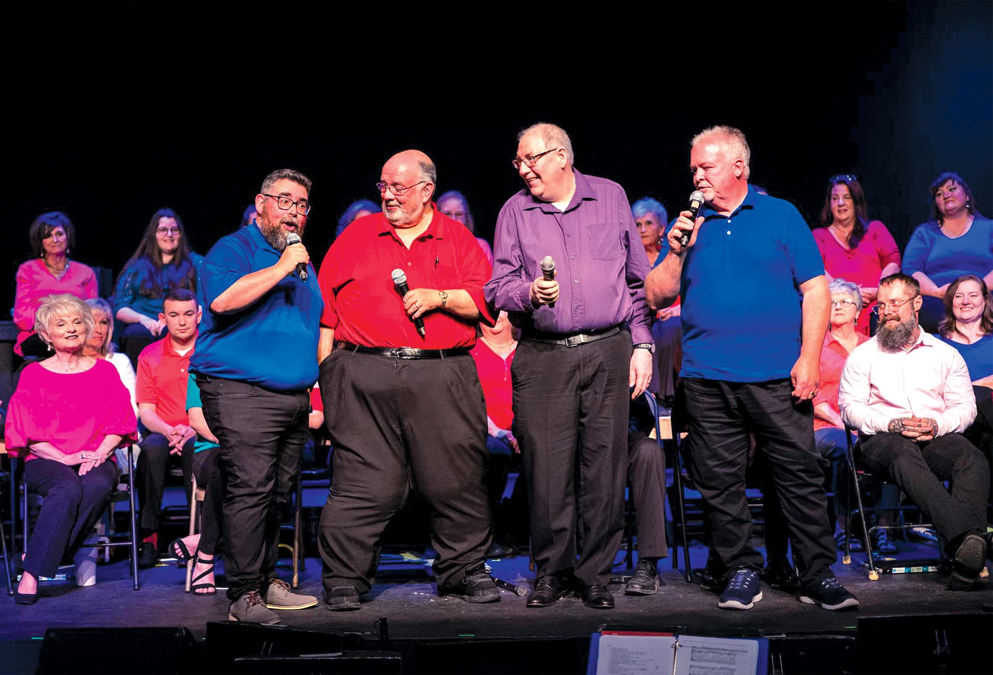 Four men holding microphones sing onstage together in a quartet during 'Looking for a City.'