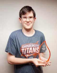 Stewart William with his Athlete of the Year award, a glass raindrop shape with orange edges.
